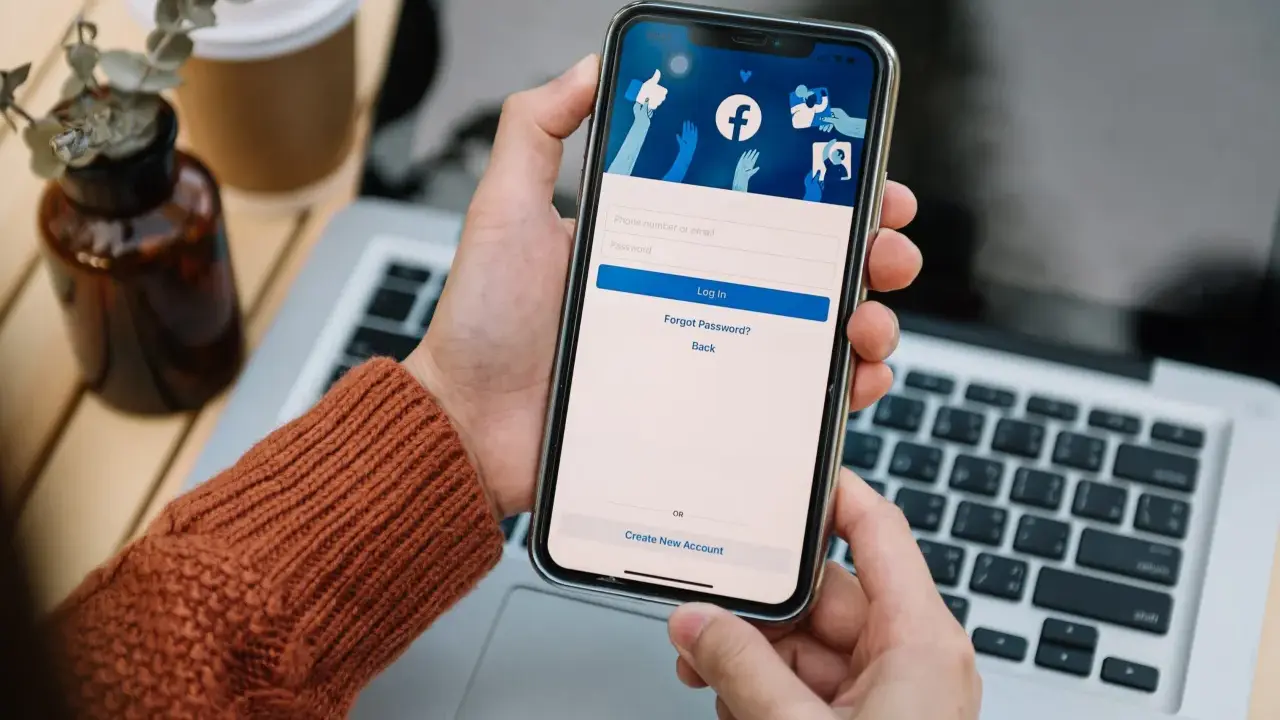 Osoba loguje się na Facebooku na telefonie. Widok ekranu logowania FB z polami na numer telefonu/email i hasło.