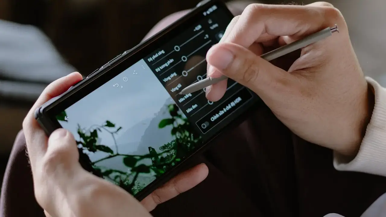 Ręce trzymają smartfon, na którym edytowany jest film. Stylus dostosowuje parametry, by pokazać, jak zrobić film na TikToku.