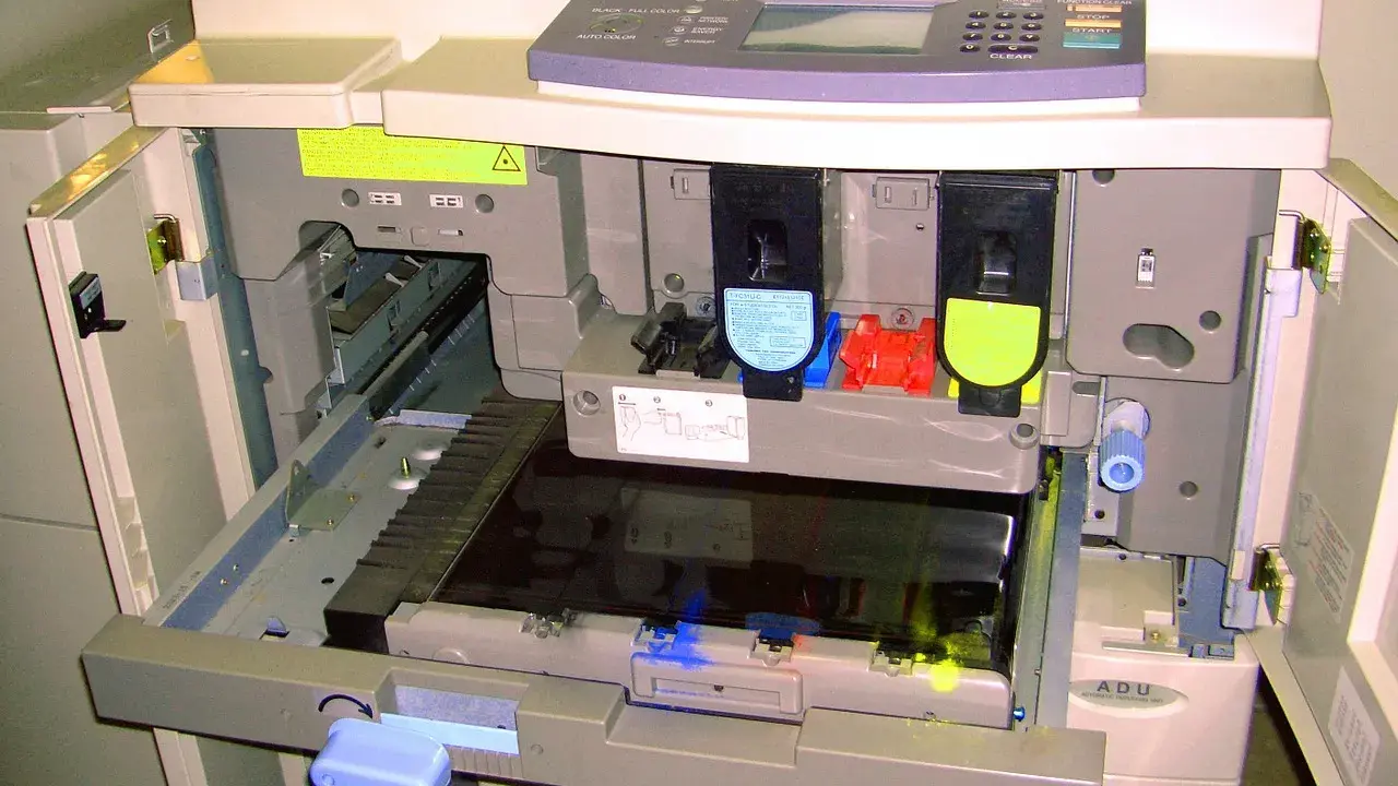 Wnętrze drukarki po otwarciu klapy, widoczne wkłady z tonerem i mechanizmy. Trwa test drukarki.