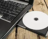 Laptop z wysuniętym napędem CD, na którym leży biała płyta. Idealne do nagrywania z cdburnerxp portable.