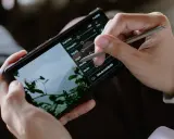 Ręce trzymają smartfon, na którym edytowany jest film. Stylus dostosowuje parametry, by pokazać, jak zrobić film na TikToku.