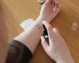 Rysunek misia na przedramieniu, utrwalany sprayem. To tymczasowy druk na kalce, który zaraz zniknie.