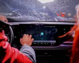 Ręka kierowcy dotyka ekranu, na którym widać ikonę Bluetooth. To nowoczesne łączenie filmów android w samochodzie.