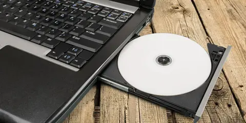 Laptop z wysuniętym napędem CD, na którym leży biała płyta. Idealne do nagrywania z cdburnerxp portable.