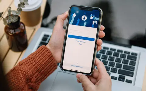 Osoba loguje się na Facebooku na telefonie. Widok ekranu logowania FB z polami na numer telefonu/email i hasło.