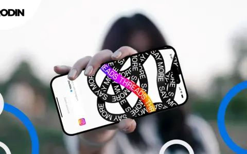 Dłoń trzyma telefon z napisem "THREADS THREADS THREADS" i hasłem "SAY MORE". Aplikacja Threads, co to?