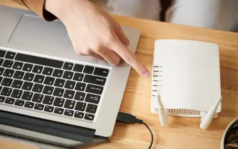Ręka wskazuje na router, podłączony do laptopa. To pierwszy krok, by skonfigurować drukarkę HP.