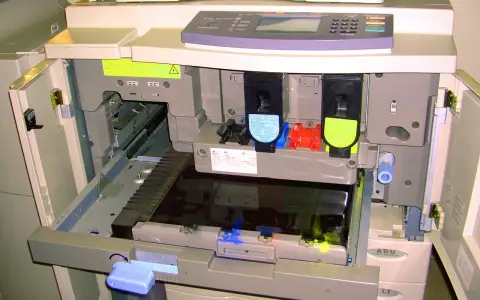Wnętrze drukarki po otwarciu klapy, widoczne wkłady z tonerem i mechanizmy. Trwa test drukarki.