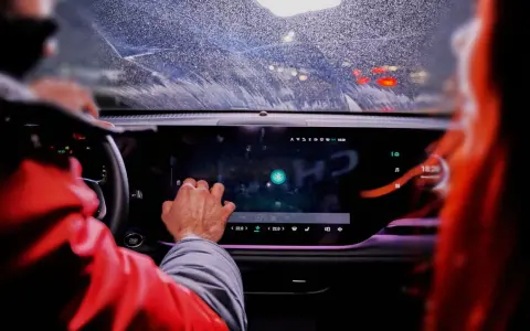 Ręka kierowcy dotyka ekranu, na którym widać ikonę Bluetooth. To nowoczesne łączenie filmów android w samochodzie.