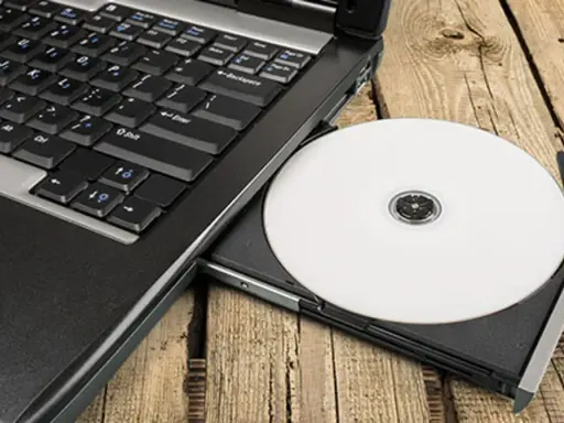 Laptop z wysuniętym napędem CD, na którym leży biała płyta. Idealne do nagrywania z cdburnerxp portable.