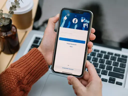 Osoba loguje się na Facebooku na telefonie. Widok ekranu logowania FB z polami na numer telefonu/email i hasło.