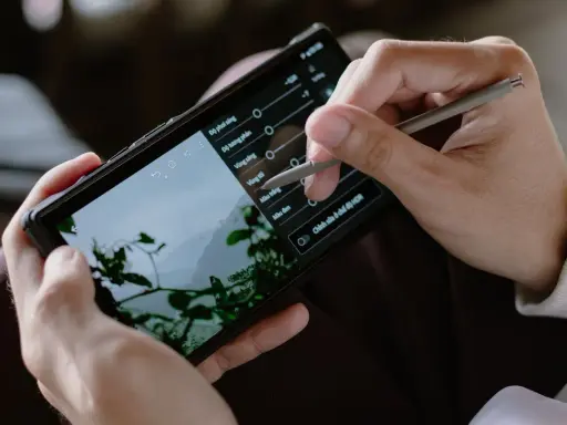 Ręce trzymają smartfon, na którym edytowany jest film. Stylus dostosowuje parametry, by pokazać, jak zrobić film na TikToku.