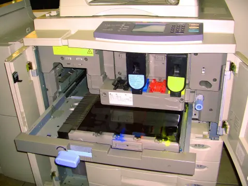 Wnętrze drukarki po otwarciu klapy, widoczne wkłady z tonerem i mechanizmy. Trwa test drukarki.