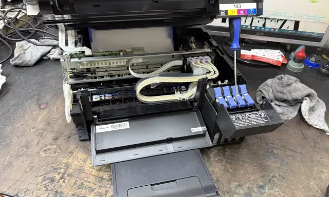 Epson czyszczenie głowicy automatyczne. Widać wnętrze drukarki, tusze i śrubokręt.