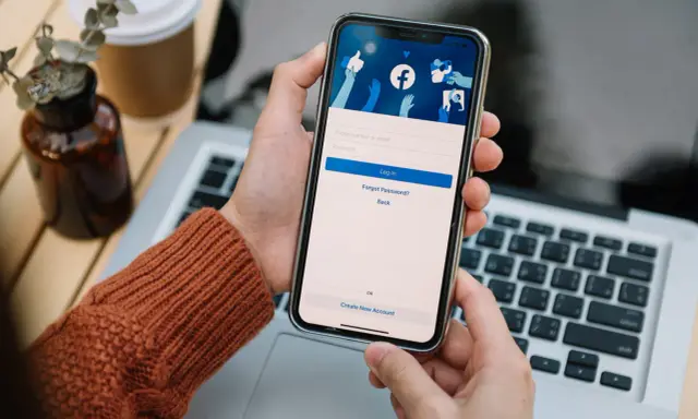 Osoba loguje się na Facebooku na telefonie. Widok ekranu logowania FB z polami na numer telefonu/email i hasło.