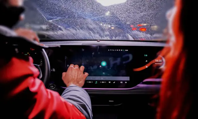 Ręka kierowcy dotyka ekranu, na którym widać ikonę Bluetooth. To nowoczesne łączenie filmów android w samochodzie.