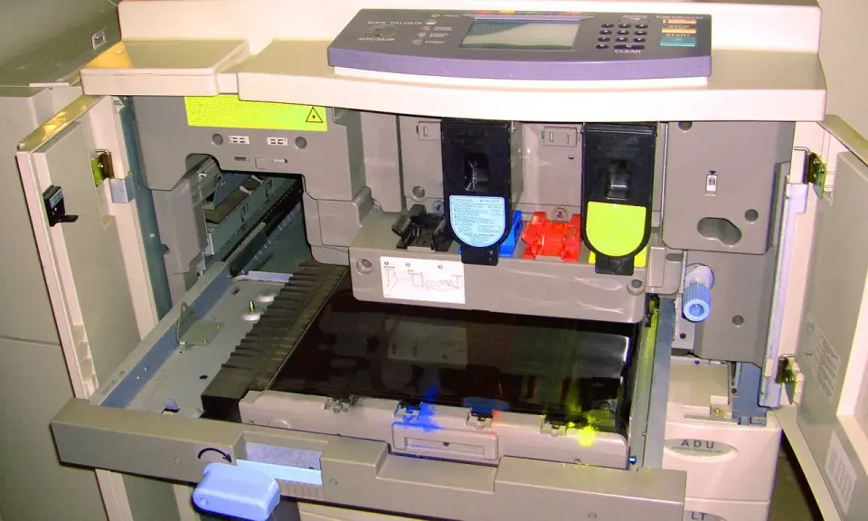 Wnętrze drukarki po otwarciu klapy, widoczne wkłady z tonerem i mechanizmy. Trwa test drukarki.